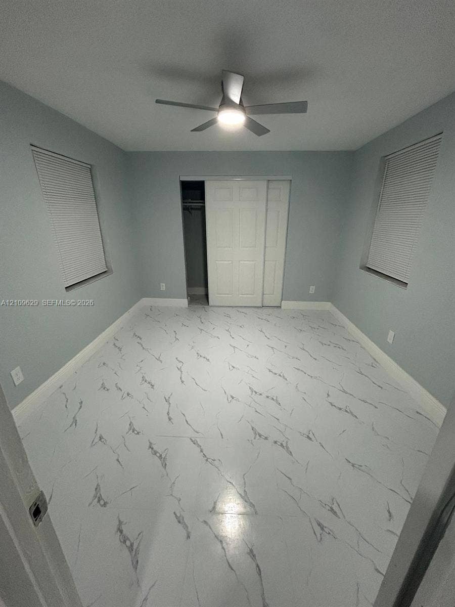 1741 NW 24th Terrace, Fort Lauderdale, FL 33311 Interior space featuring light-toned, high-contrast patterned flooring, dual windows with integrated blinds, a ceiling fan with integrated lighting, and a closet with sliding paneled doors