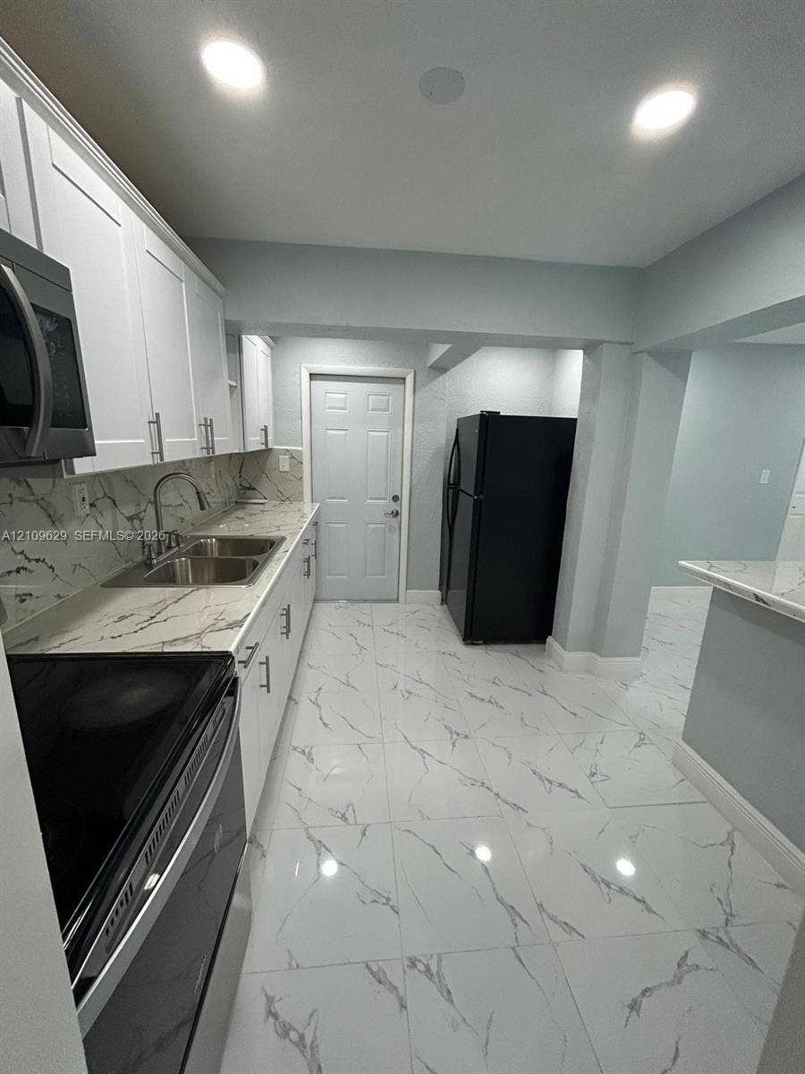 1741 NW 24th Terrace, Fort Lauderdale, FL 33311 Kitchen featuring white shaker-style cabinetry, stone-patterned countertops, large-format tiled flooring, recessed lighting, and integrated stainless steel microwave