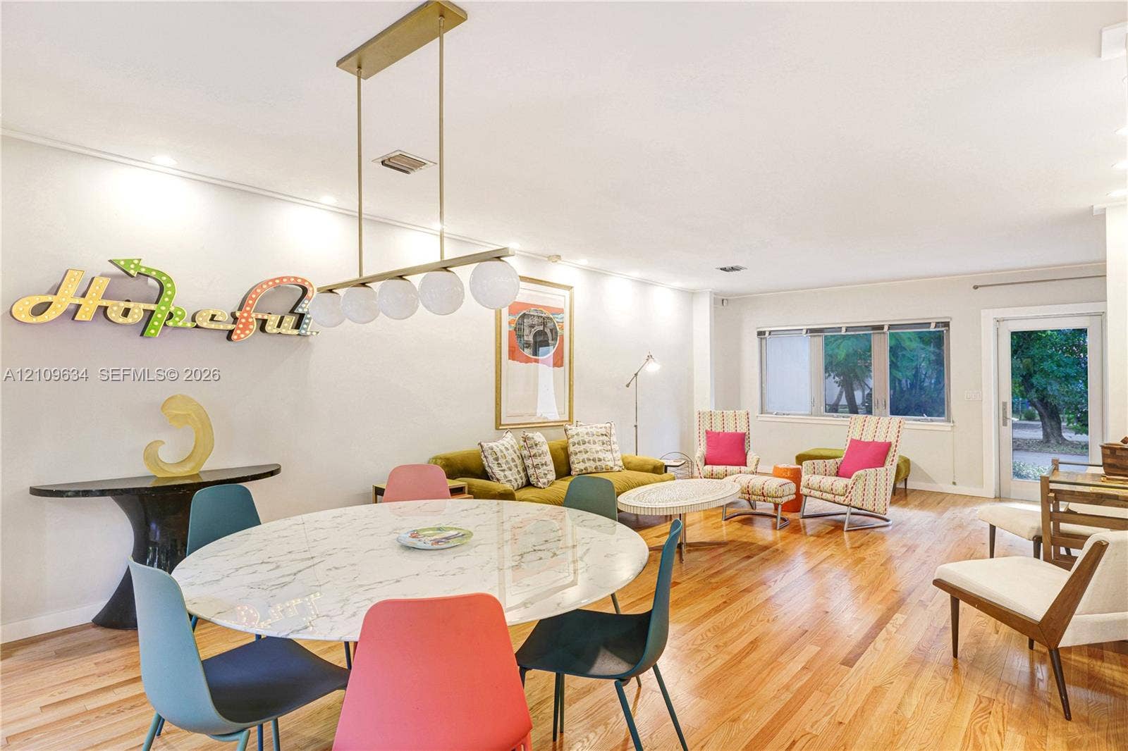 Open-concept living space featuring wood-finish flooring, multi-globe linear chandelier, recessed lighting, and large windows