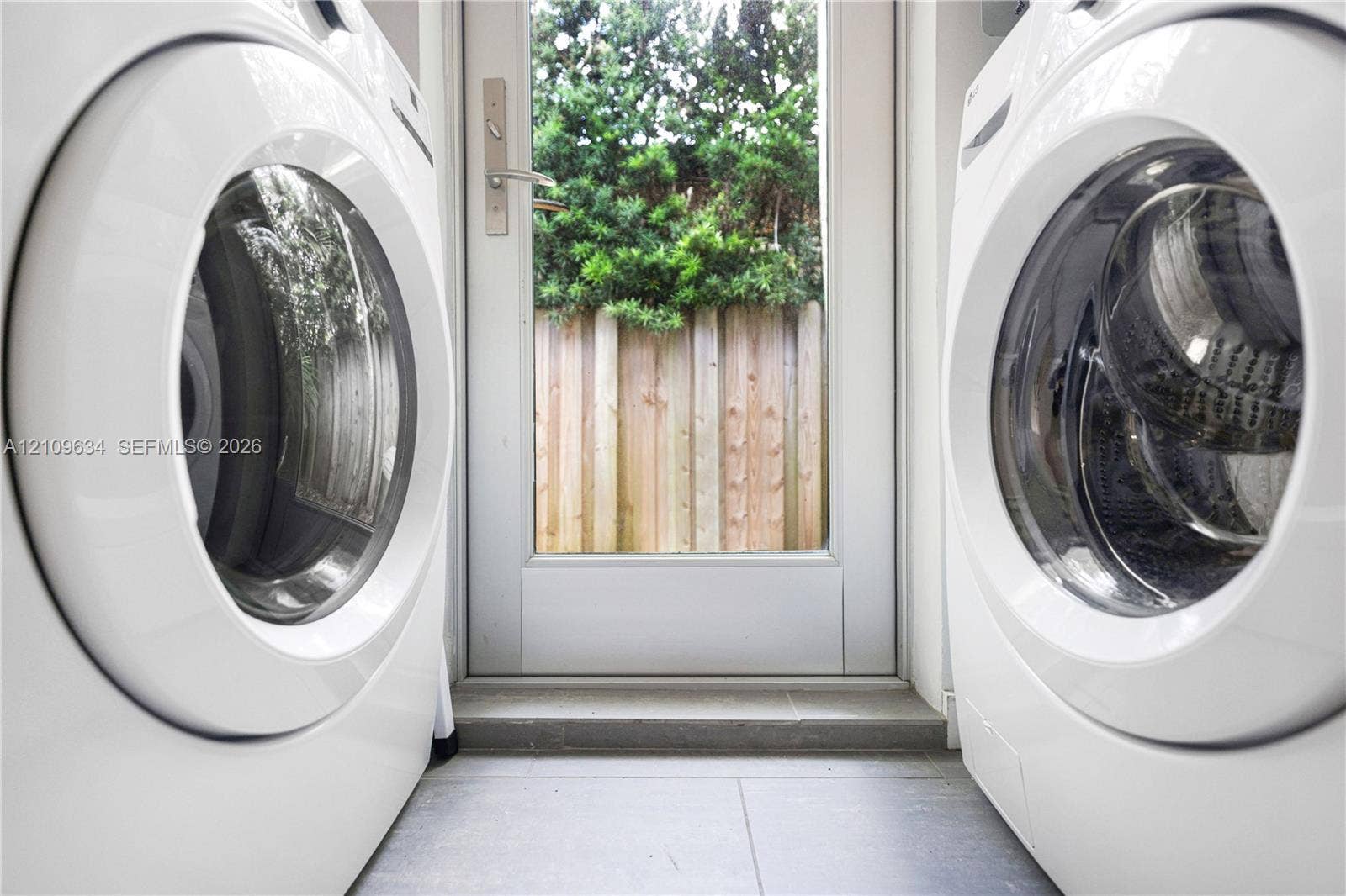 Laundry area featuring large-format tile flooring and a glass-paneled exterior door with brushed metal hardware