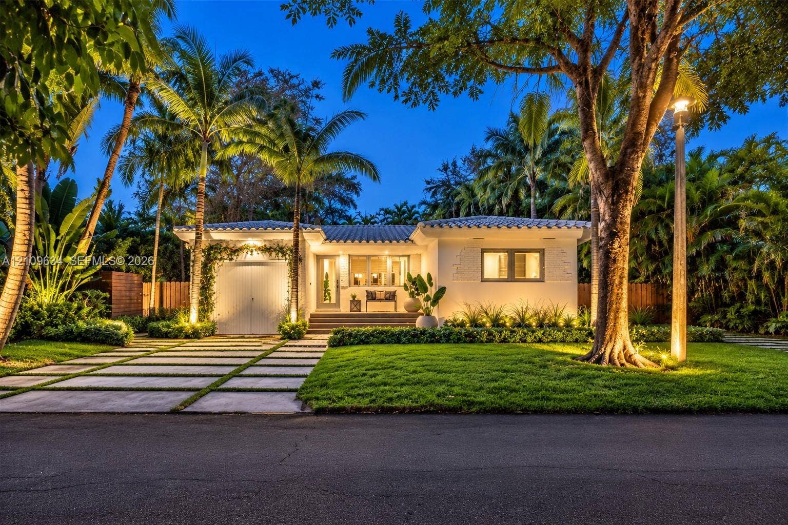 Single-story exterior featuring a light-toned stucco faade, a multi-paneled garage door, a tiled roof, and a paved grid-pattern driveway