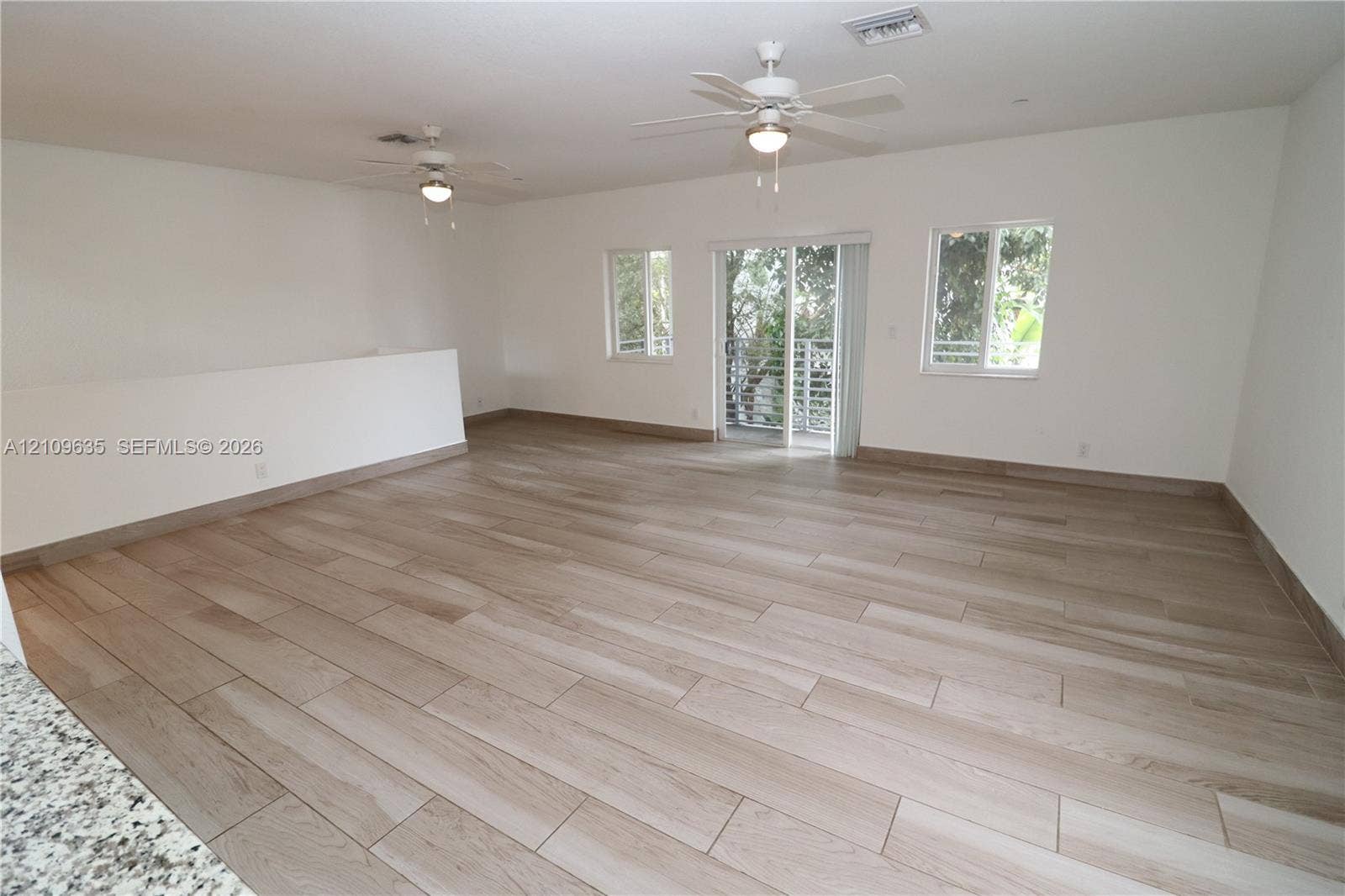 611 NE 28th Street, #1, Wilton Manors, Wilton Manors, FL 33334 Open-concept interior featuring light wood-finish flooring, dual ceiling fans, sliding glass doors, and large windows