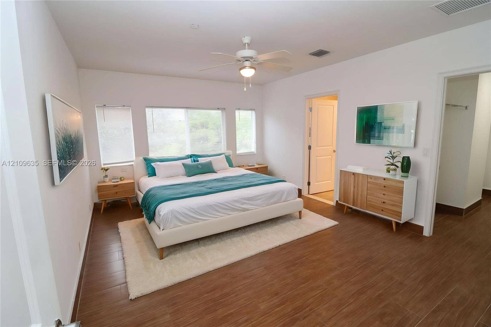 611 NE 28th Street, #1, Wilton Manors, Wilton Manors, FL 33334 Bedroom featuring wood-finish tile flooring, three paneled windows, and a central ceiling fan with integrated lighting