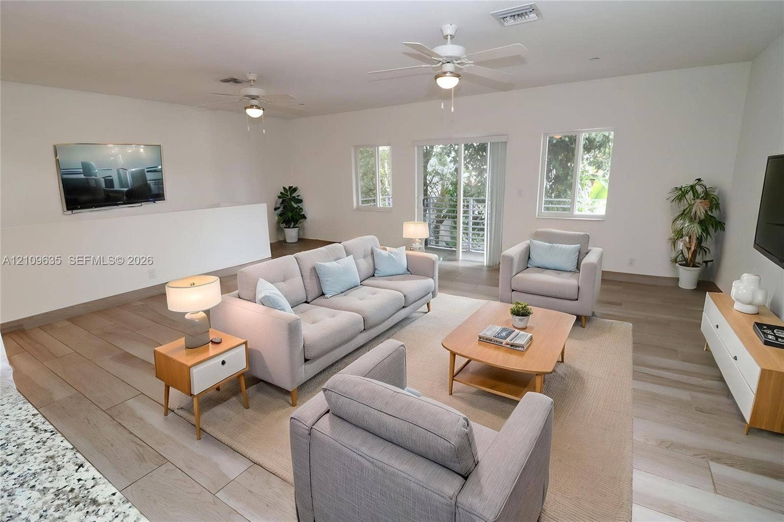 611 NE 28th Street, #1, Wilton Manors, Wilton Manors, FL 33334 Open-concept interior featuring wood-finish flooring, recessed ceiling lighting, dual ceiling fans, and sliding glass doors with exterior access