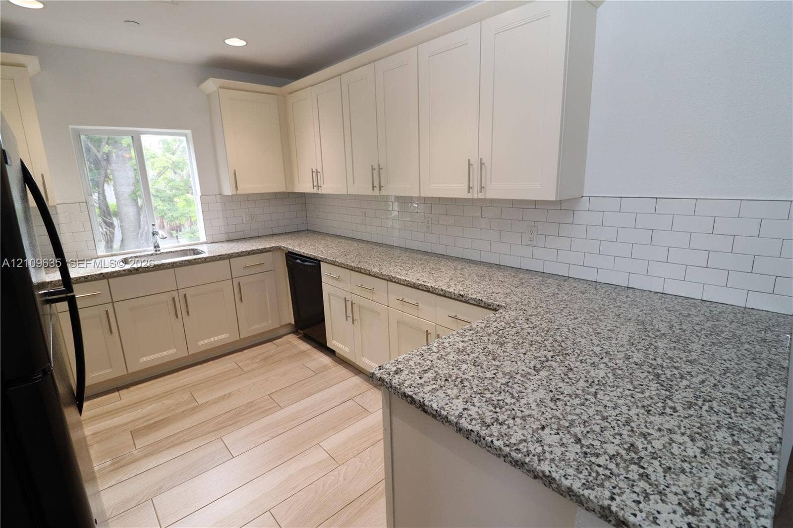 611 NE 28th Street, #1, Wilton Manors, Wilton Manors, FL 33334 Kitchen featuring light-toned cabinetry, stone-finish countertops, subway tile backsplash, wood-finish flooring, and recessed ceiling lighting