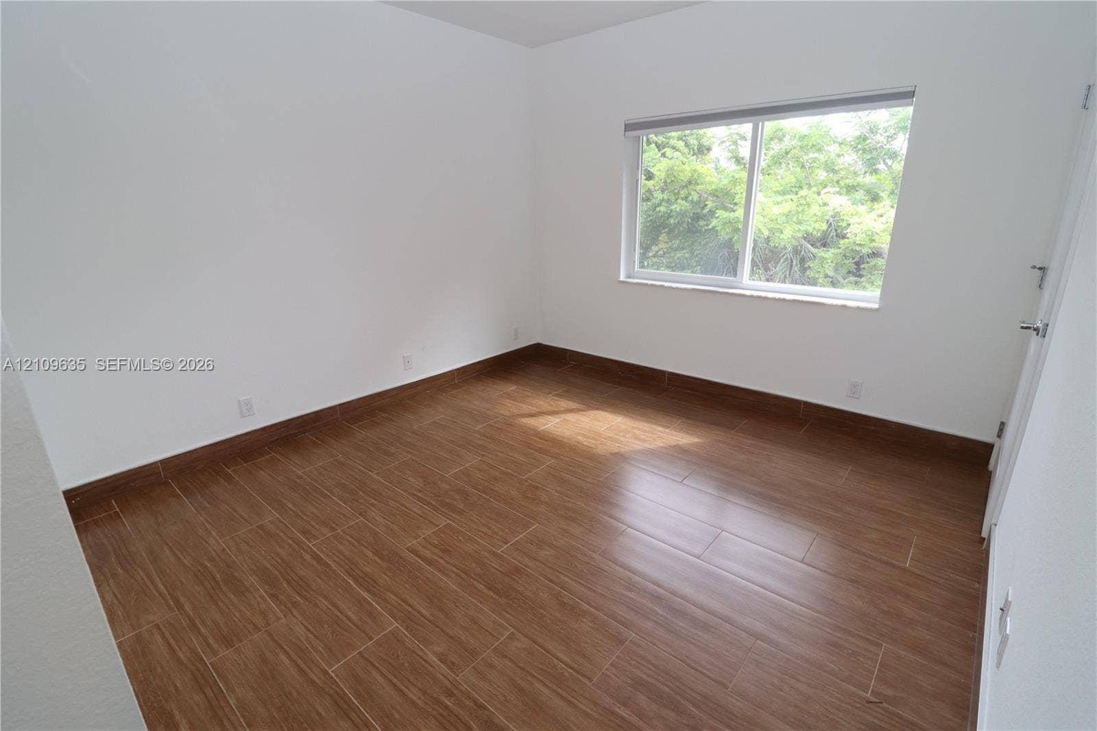 611 NE 28th Street, #1, Wilton Manors, Wilton Manors, FL 33334 Neutral wall tones, wood-finish flooring, and a large window featuring horizontal blinds