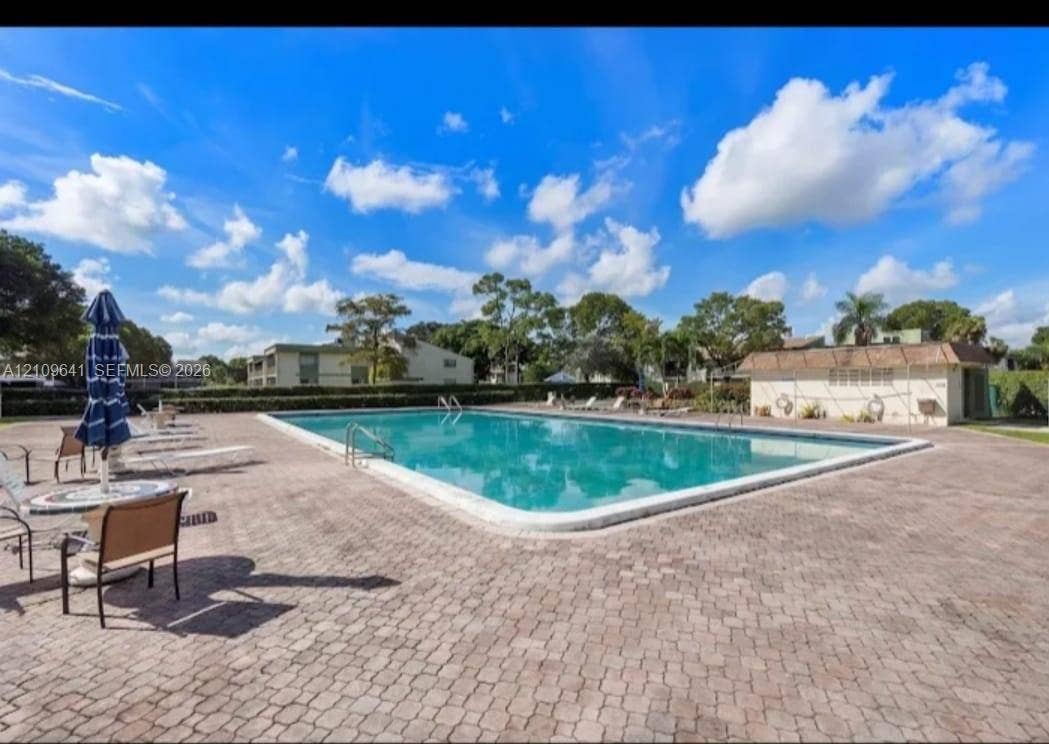 4108 NW 88th Avenue, #4, Coral Springs, Coral Springs, FL 33065 Rectangular swimming pool featuring a brick paver deck, metal safety handrails, and a nearby utility structure