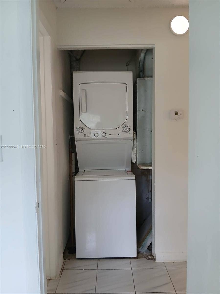 4108 NW 88th Avenue, #4, Coral Springs, Coral Springs, FL 33065 Laundry closet containing a stacked washer and dryer unit, featuring white ceramic tile flooring and a wall-mounted light fixture