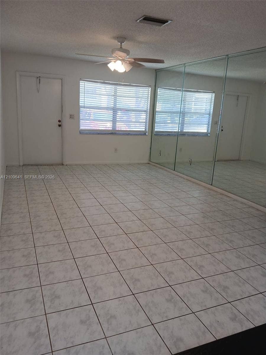 4108 NW 88th Avenue, #4, Coral Springs, Coral Springs, FL 33065 Room interior featuring large-format tile flooring, wall-to-wall mirrored panels, a ceiling fan with integrated lighting, and a single-pane window