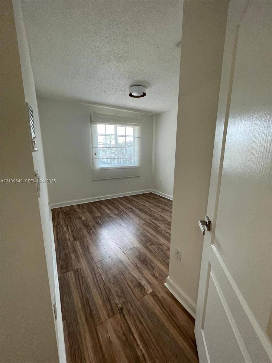 11467 NW 51st Terrace, Doral, Doral, FL 33178 Room featuring wood-finish flooring, a multi-pane window with a built-in blind, and a central flush-mount ceiling light fixture