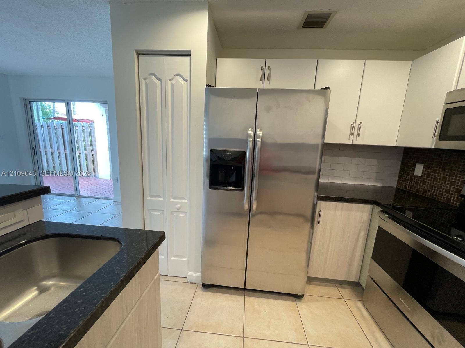 11467 NW 51st Terrace, Doral, Doral, FL 33178 Kitchen featuring white cabinetry, dark countertops, a tile backsplash, stainless steel appliances, and tile flooring