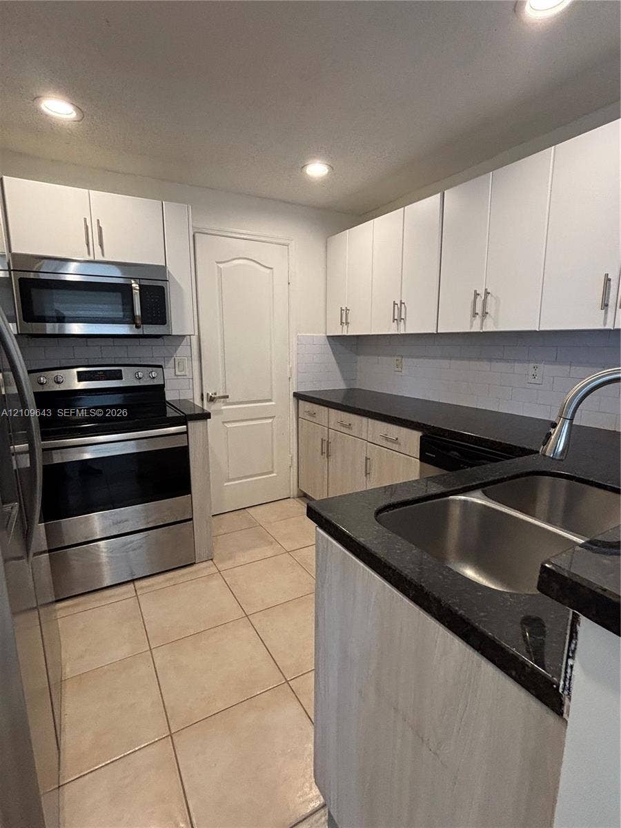 11467 NW 51st Terrace, Doral, Doral, FL 33178 Kitchen featuring stainless steel appliances, dark stone-finish countertops, subway tile backsplash, recessed lighting, and white cabinetry
