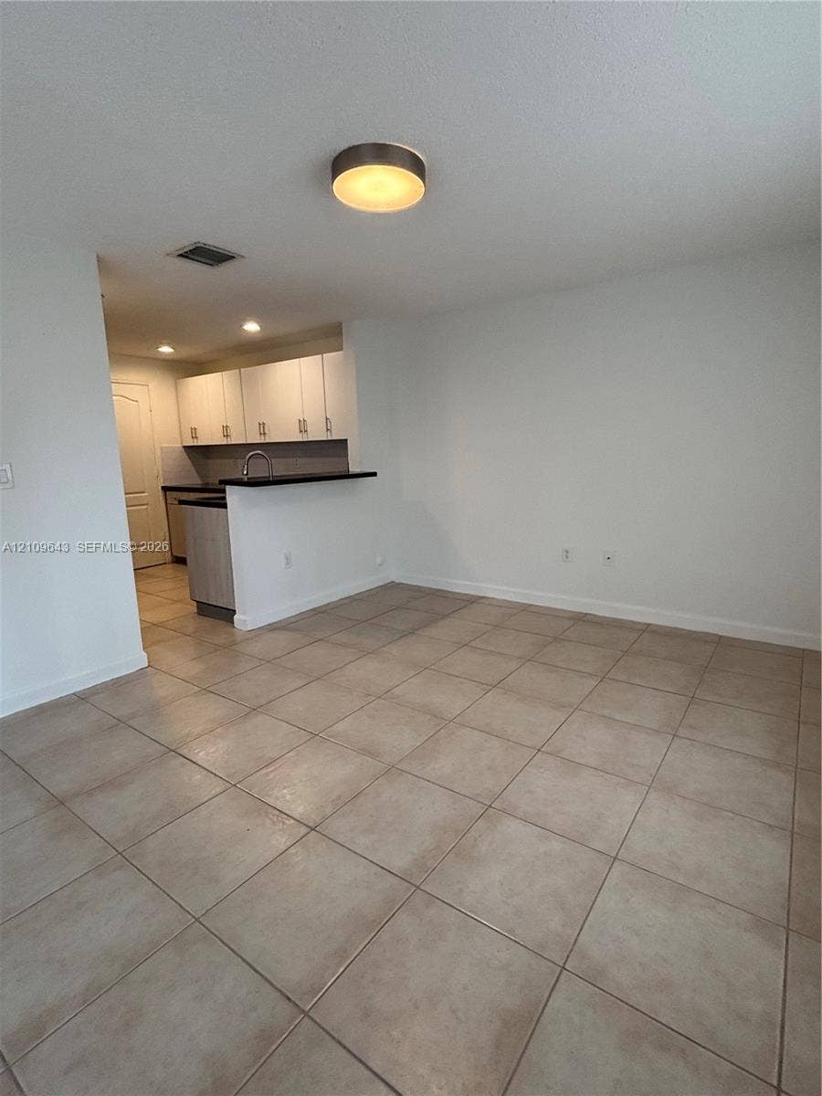 11467 NW 51st Terrace, Doral, Doral, FL 33178 Ceramic tile flooring throughout the main space, featuring kitchen cabinetry with contrasting dark countertops, a stainless steel kitchen faucet, and a flush-mount circular ceiling fixture