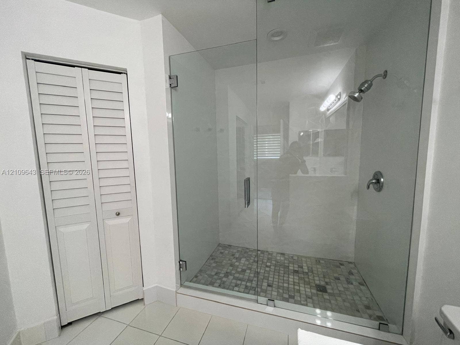11467 NW 51st Terrace, Doral, Doral, FL 33178 Walk-in shower featuring a frameless glass enclosure, pebble-tile flooring, and metallic fixtures