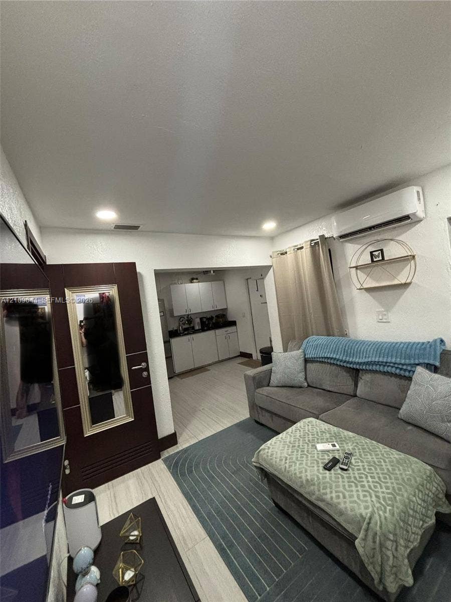 1881 SW 42nd Terrace, #2, Fort Lauderdale, Fort Lauderdale, FL 33317 Living space featuring wood-finish flooring, recessed lighting, wall-mounted ductless air conditioning unit, and a dark-toned interior door with integrated mirror
