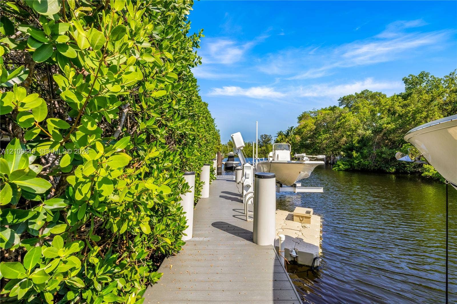 332 Costanera Road, Coral Gables, FL 33143 Waterfront dock featuring composite decking, vertical pilings, and a mechanical boat lift
