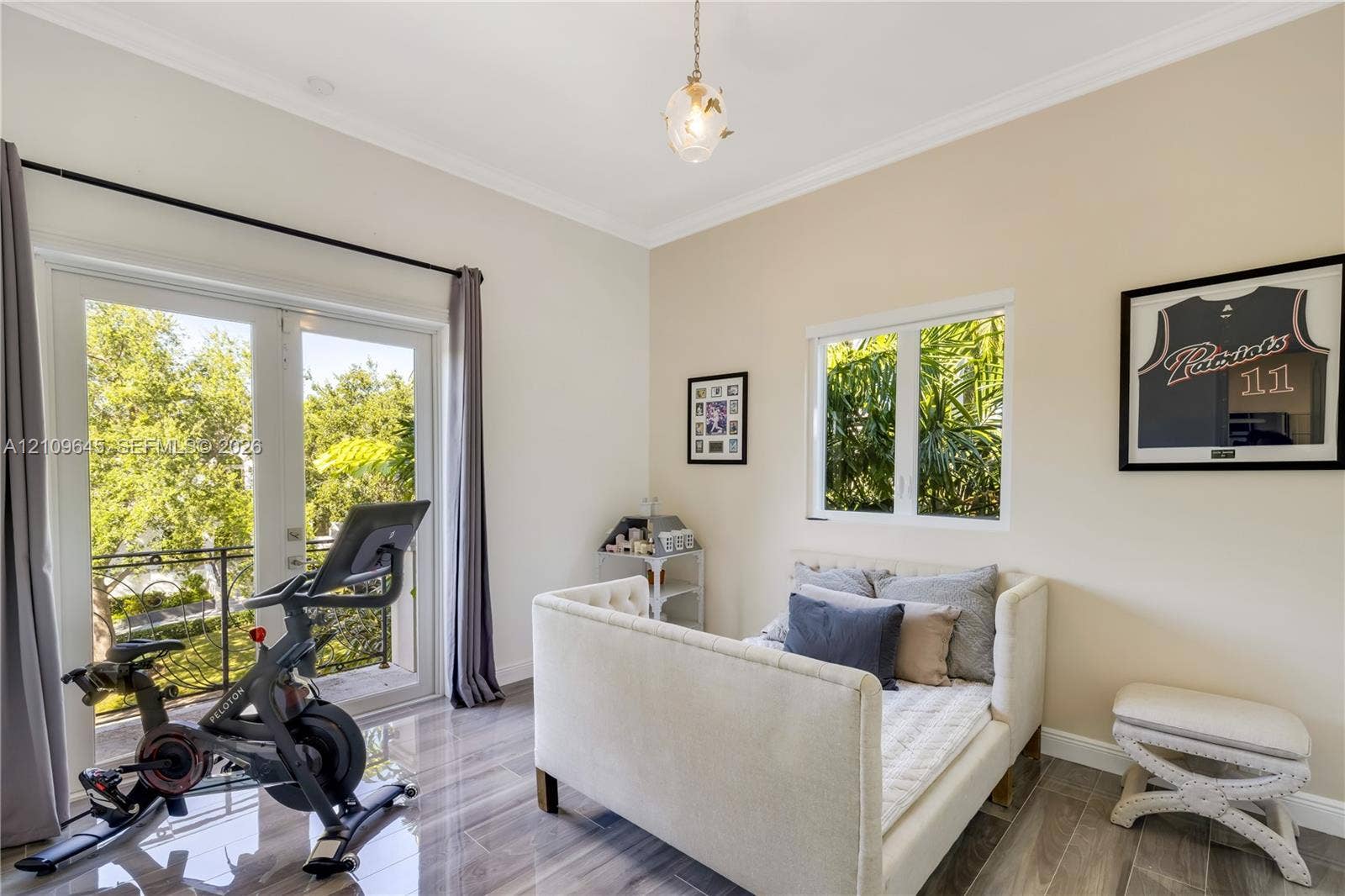 332 Costanera Road, Coral Gables, FL 33143 Room featuring wood-finish tile flooring, crown molding, glass-paned French doors opening to a balcony with decorative railing, and a pendant light fixture