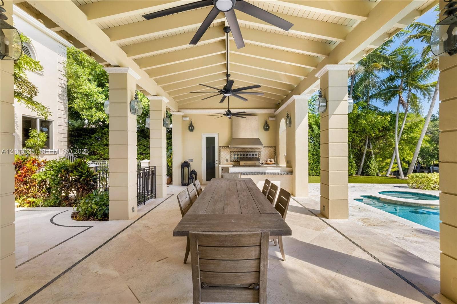 332 Costanera Road, Coral Gables, FL 33143 Covered outdoor terrace featuring a built-in kitchen, stone-tile flooring, decorative masonry columns, and recessed ceiling fans