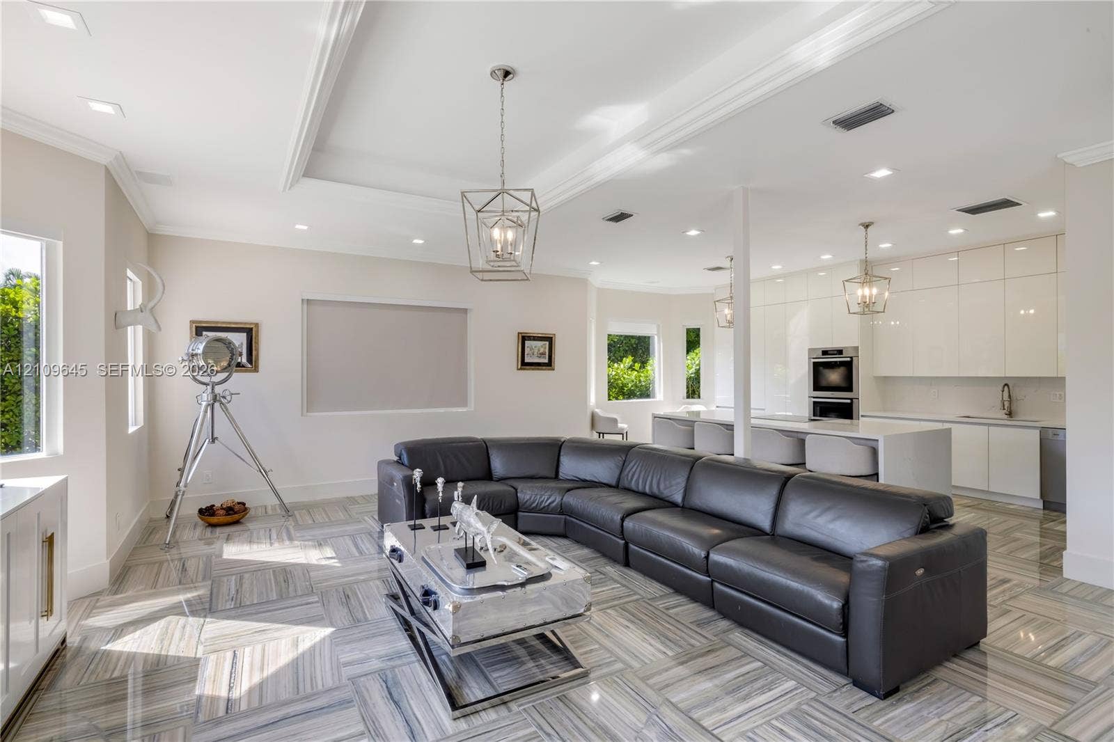 332 Costanera Road, Coral Gables, FL 33143 Open-concept area featuring high-gloss cabinetry, stone tile flooring, tray ceilings, recessed lighting, and a kitchen island with integrated sink