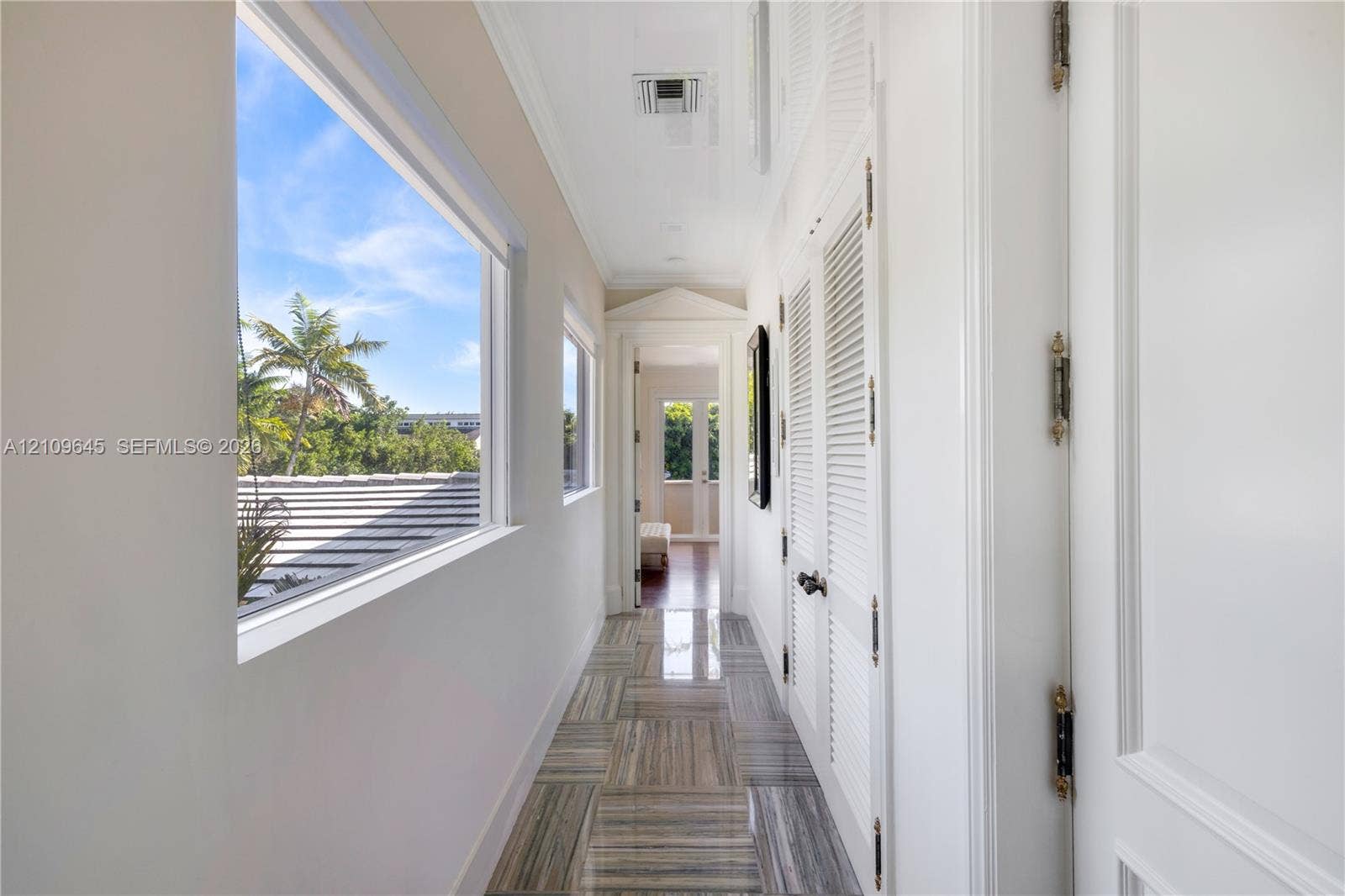 332 Costanera Road, Coral Gables, FL 33143 Hallway featuring polished stone flooring, louvered closet doors, crown molding, and large windows