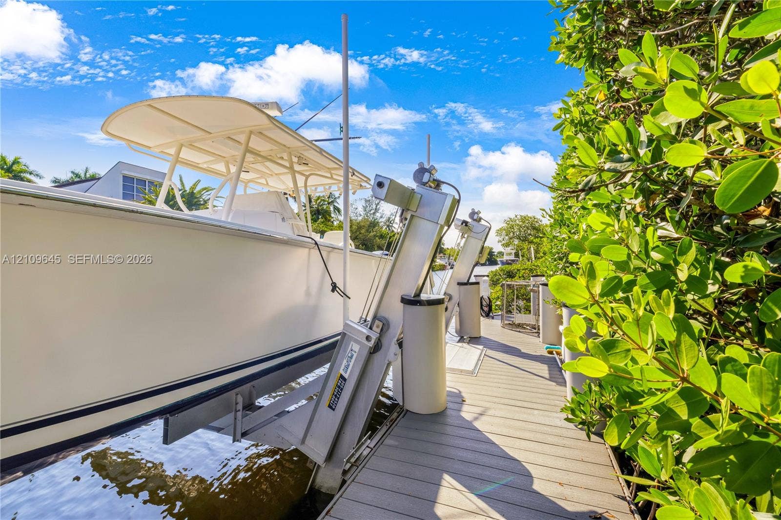 332 Costanera Road, Coral Gables, FL 33143 Private dock featuring a mechanical boat lift, composite decking, and mature landscaping