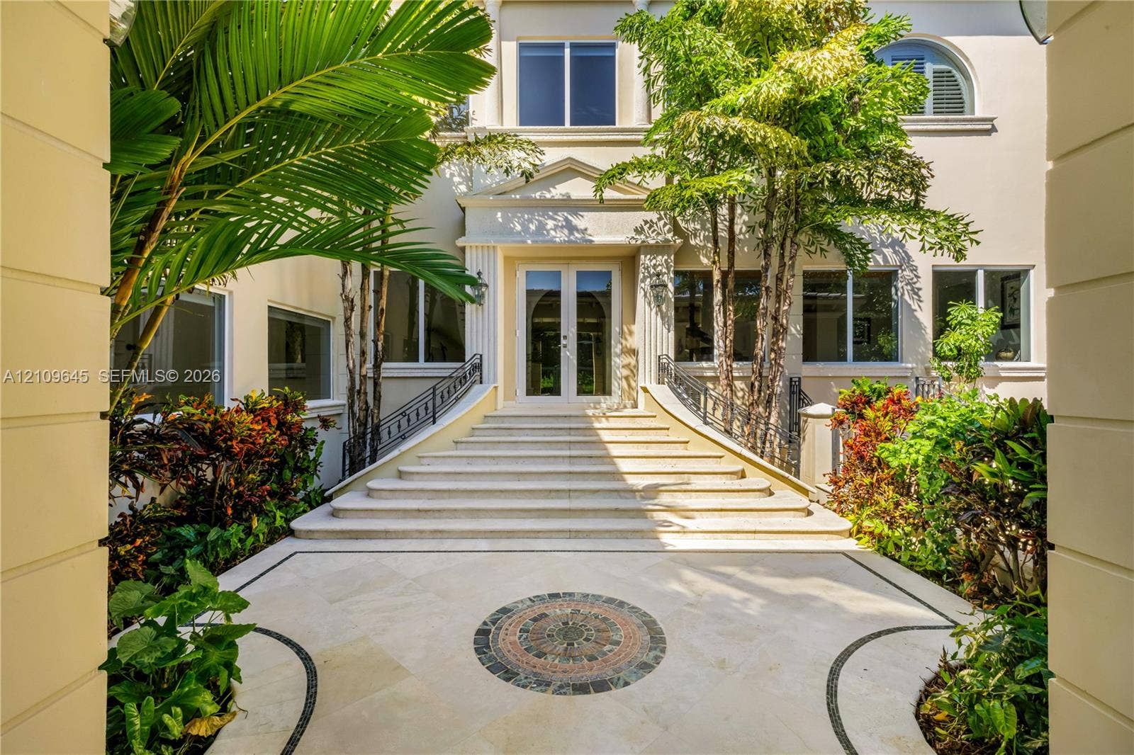 332 Costanera Road, Coral Gables, FL 33143 Grand entrance featuring a stone staircase, detailed tile inlay, symmetrical wrought iron railings, and dual glass-paned entry doors