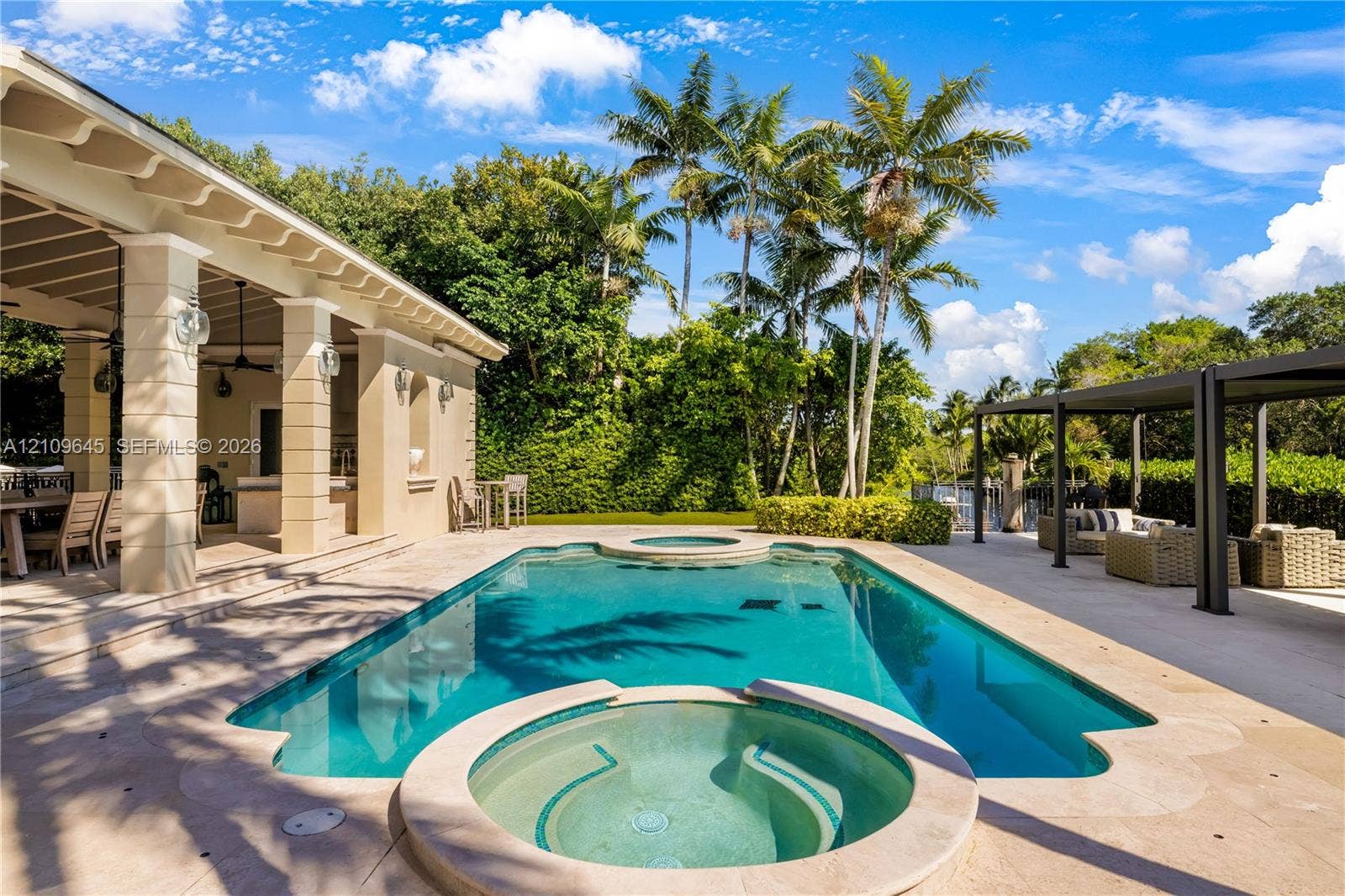 332 Costanera Road, Coral Gables, FL 33143 Swimming pool with integrated spa, covered lanai featuring structural columns, paver decking, and metal pergola