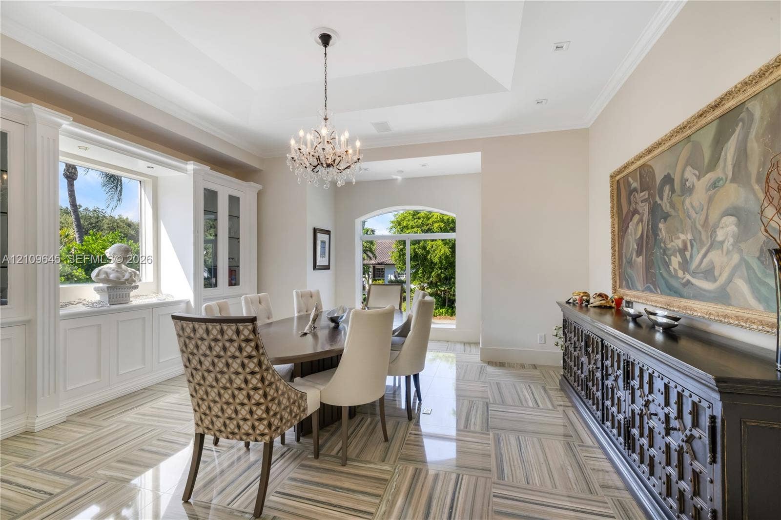 332 Costanera Road, Coral Gables, FL 33143 Tray ceiling featuring a central crystal chandelier, polished stone flooring, custom built-in cabinetry, and arched windows