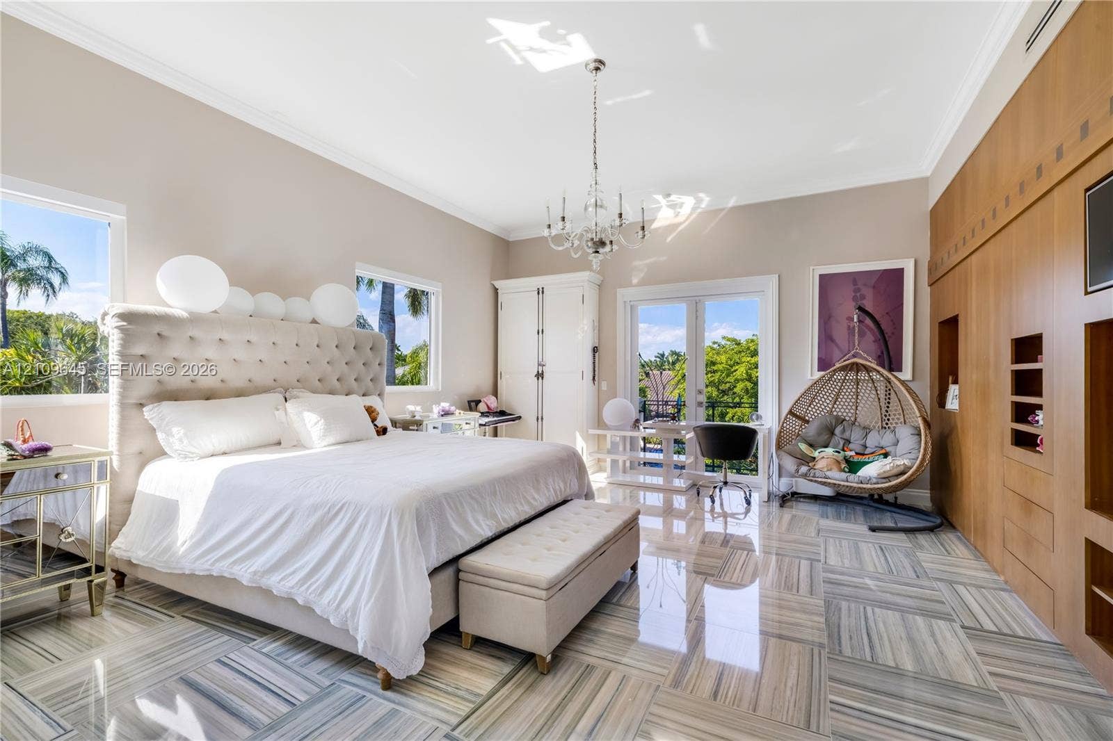 332 Costanera Road, Coral Gables, FL 33143 Polished natural stone flooring, custom floor-to-ceiling wood cabinetry, recessed crown molding, crystal chandelier, and French doors
