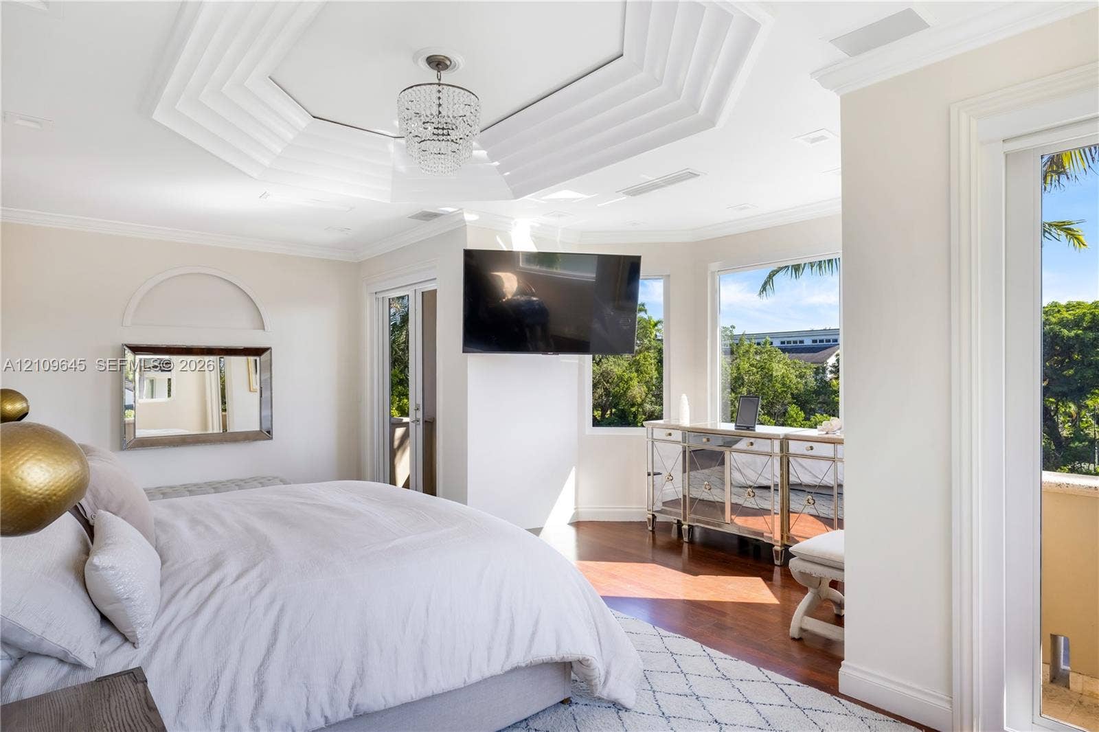 332 Costanera Road, Coral Gables, FL 33143 Octagonal tray ceiling featuring crown molding and a crystal chandelier, wood-finish flooring, and large windows with exterior foliage