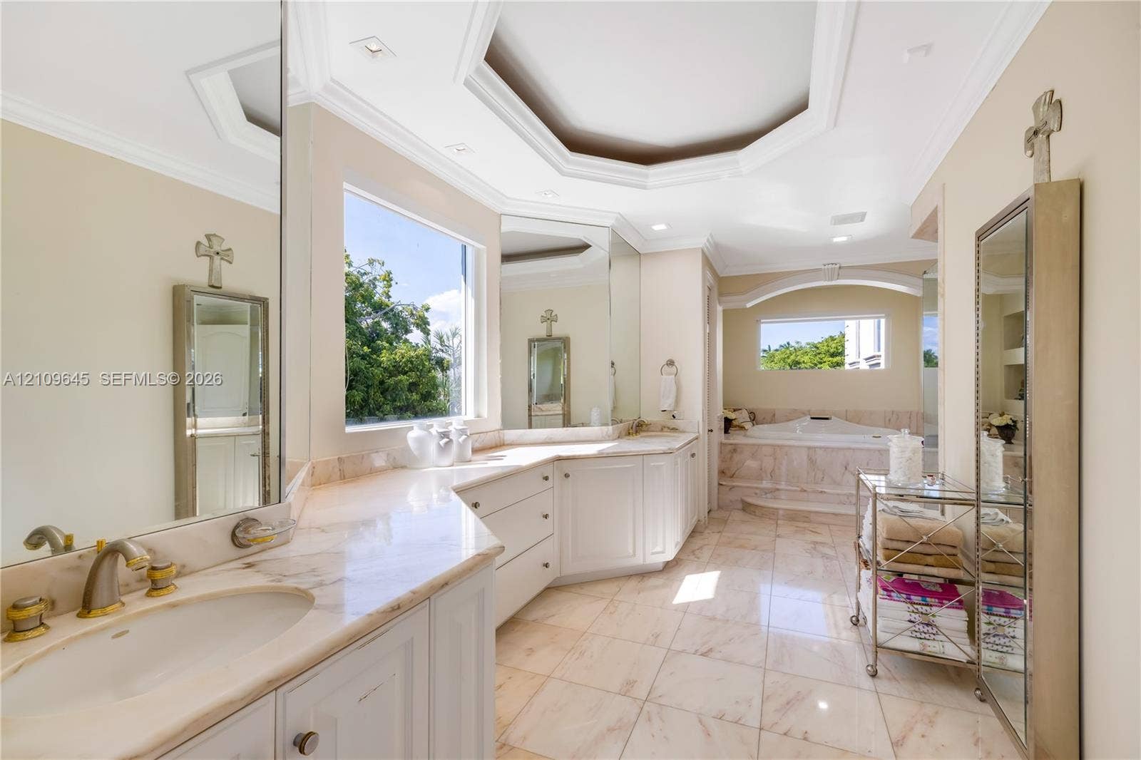 332 Costanera Road, Coral Gables, FL 33143 Bathroom featuring stone-finish flooring, white built-in cabinetry with stone countertops, an inset soaking tub with a stone surround, and an octagonal tray ceiling