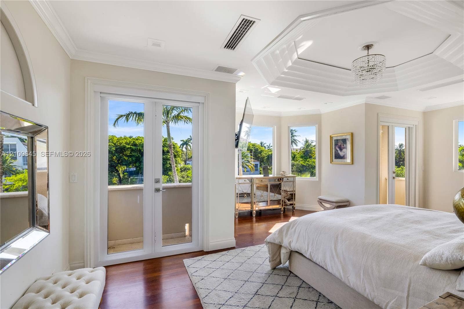 332 Costanera Road, Coral Gables, FL 33143 Octagonal tray ceiling with inset crown molding, polished wood-finish flooring, dual-pane glass entry doors, and multi-light crystal chandelier