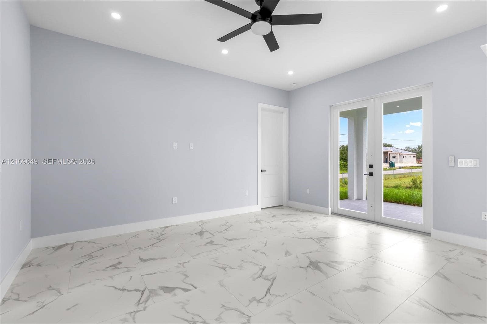 2818 42nd St Sw Lehigh Acres, Lehigh Acres, FL 33976 Large-format stone-patterned tile flooring, recessed ceiling lighting, matte black ceiling fan, and full-lite glass French doors
