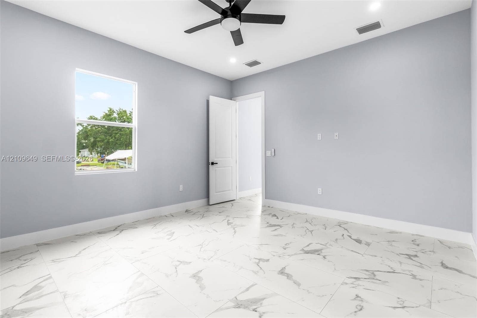 2818 42nd St Sw Lehigh Acres, Lehigh Acres, FL 33976 Neutral-toned room featuring large-format stone-patterned tile flooring, a multi-speed ceiling fan, recessed lighting, and a single-hung window