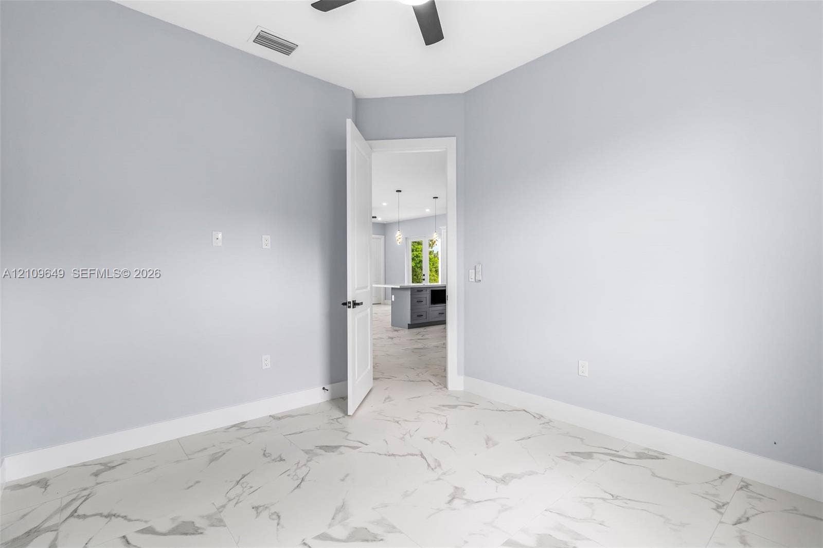 2818 42nd St Sw Lehigh Acres, Lehigh Acres, FL 33976 Room featuring large-format tile flooring with a veined pattern, neutral wall paint, and a ceiling-mounted fan