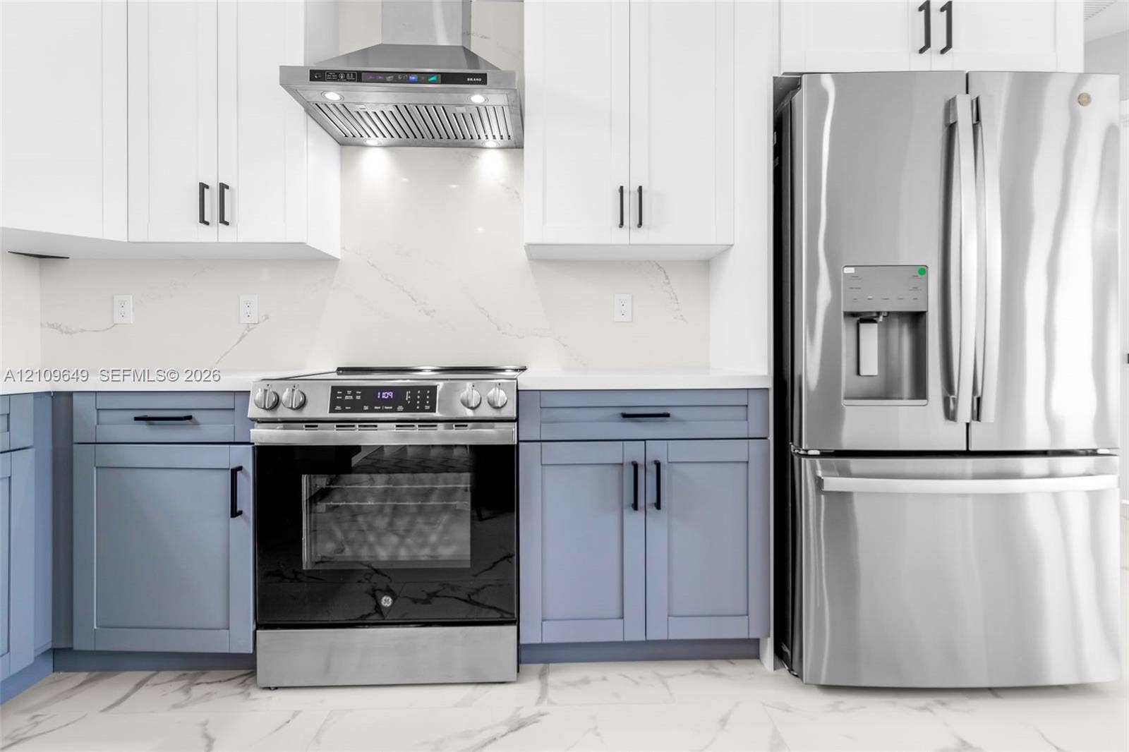 2818 42nd St Sw Lehigh Acres, Lehigh Acres, FL 33976 Kitchen featuring two-tone cabinetry with matte black hardware, stainless steel appliances, stone-look backsplash, and stone-look countertops