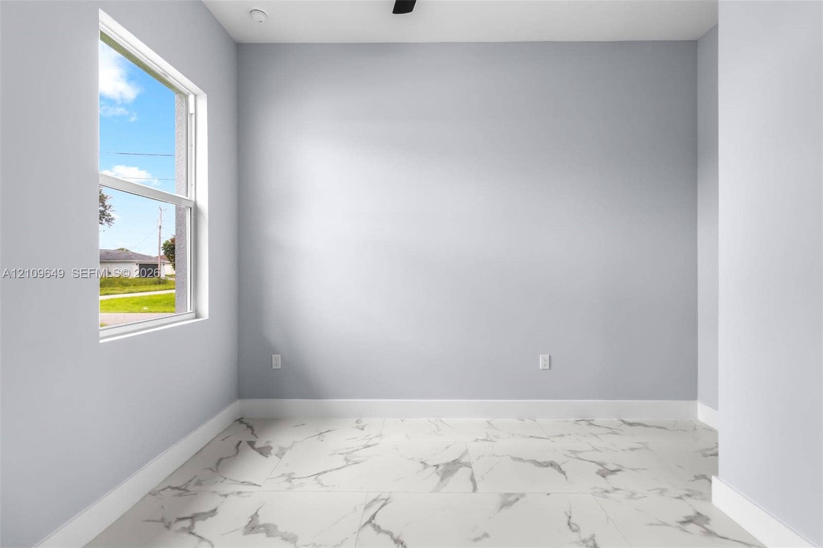 2818 42nd St Sw Lehigh Acres, Lehigh Acres, FL 33976 Interior space featuring large-format tile flooring with a marble-finish pattern, light-toned wall paint, and a single-hung window
