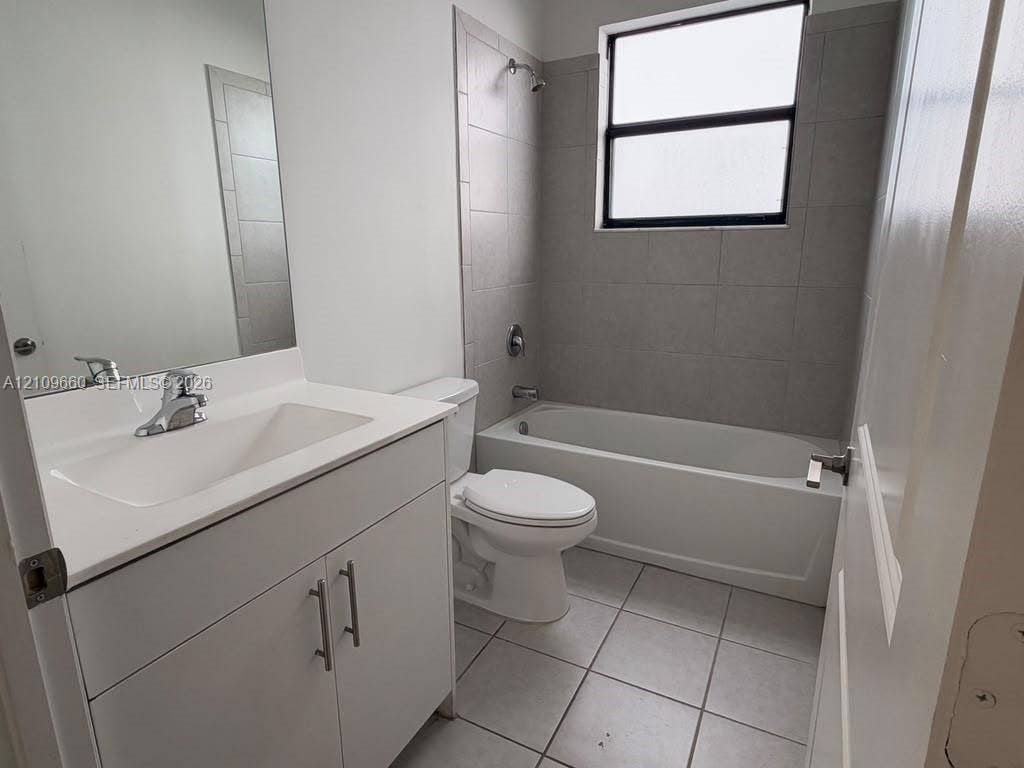 23275 SW 133 Rd Avenue, #2, Homestead, Homestead, FL 33032 Bathroom featuring a white vanity cabinet with an integrated basin, wall-to-wall mirror, tiled flooring, and a bathtub with a tiled surround