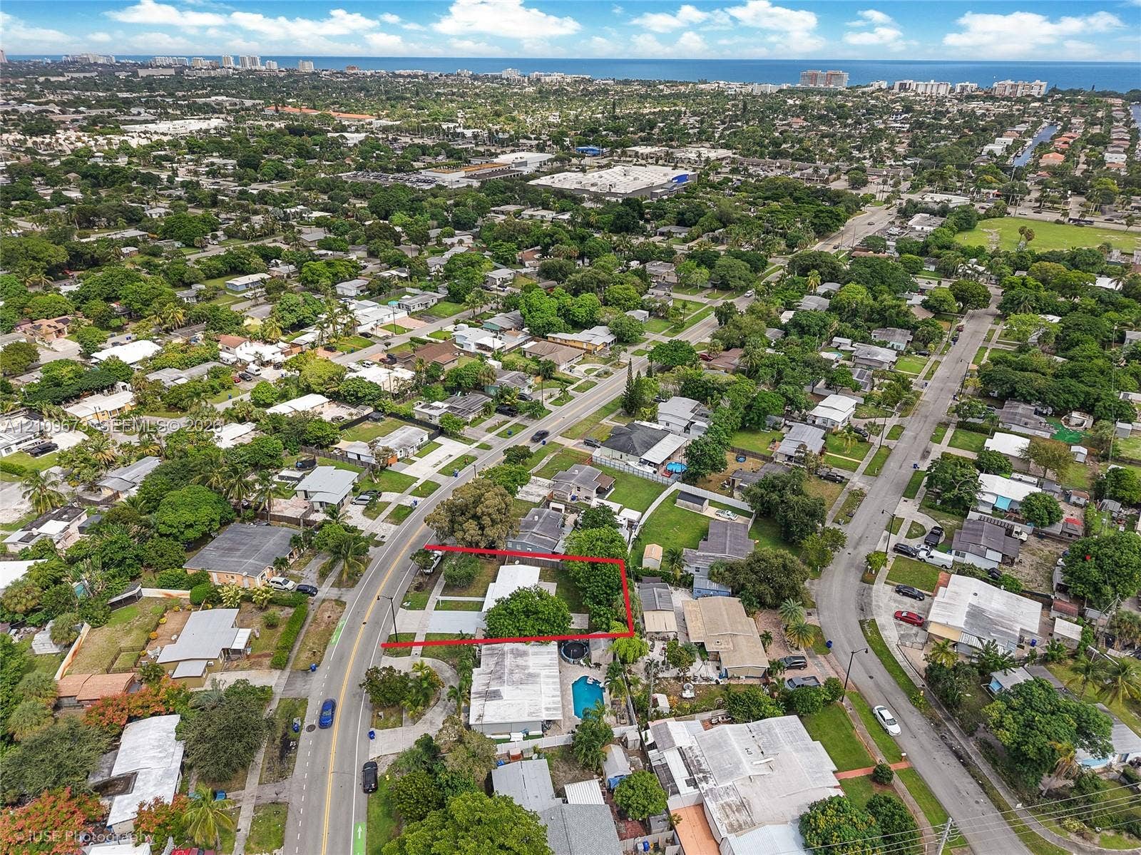 1748 NE 49th Street, Pompano Beach, FL 33064 Aerial perspective of a residential lot featuring a concrete driveway and mature tree canopy