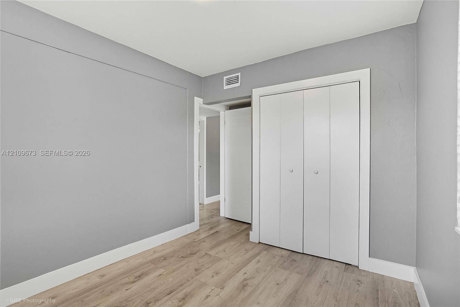 1748 NE 49th Street, Pompano Beach, FL 33064 Interior space featuring neutral gray walls, wood-finish flooring, and a white bi-fold closet door
