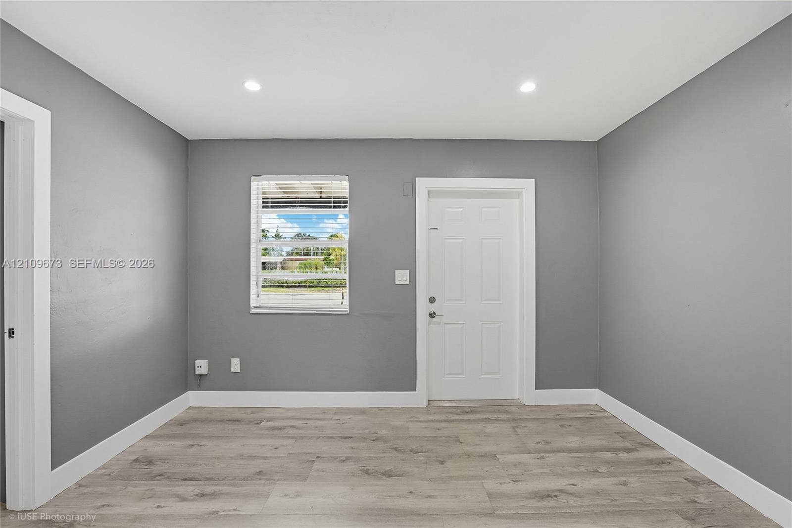 1748 NE 49th Street, Pompano Beach, FL 33064 Interior space featuring wood-finish flooring, neutral gray walls, recessed lighting, and a six-panel door
