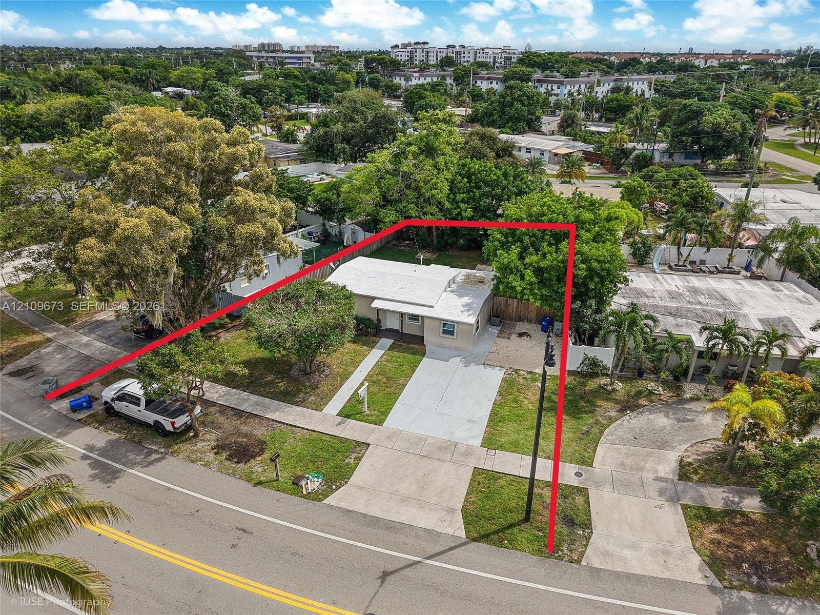 1748 NE 49th Street, Pompano Beach, FL 33064 Detached residence featuring a concrete driveway, established trees, and perimeter fencing
