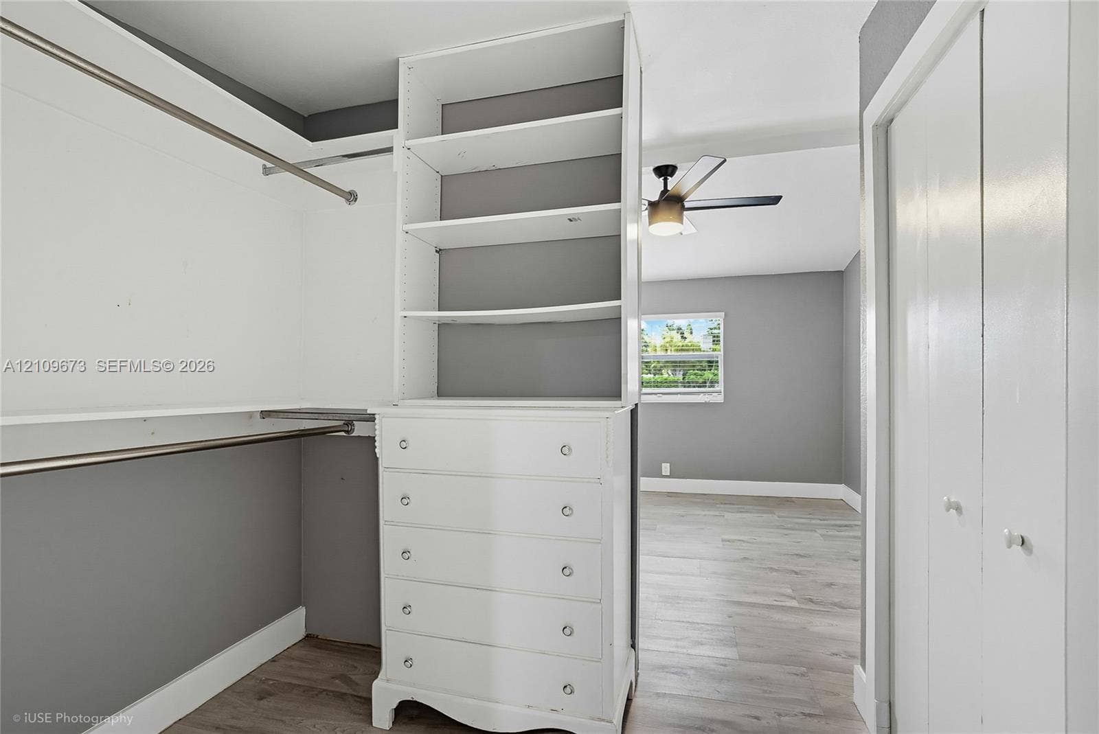 1748 NE 49th Street, Pompano Beach, FL 33064 Walk-in closet featuring built-in white cabinetry with open shelving and drawers, wood-finish flooring, and dual hanging rods