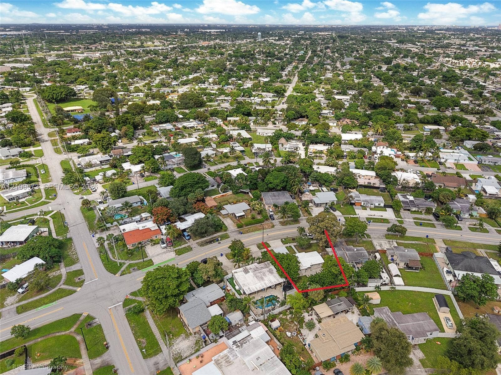 1748 NE 49th Street, Pompano Beach, FL 33064 Aerial perspective of a corner lot situated in a suburban residential setting, featuring mature trees and street-level frontage
