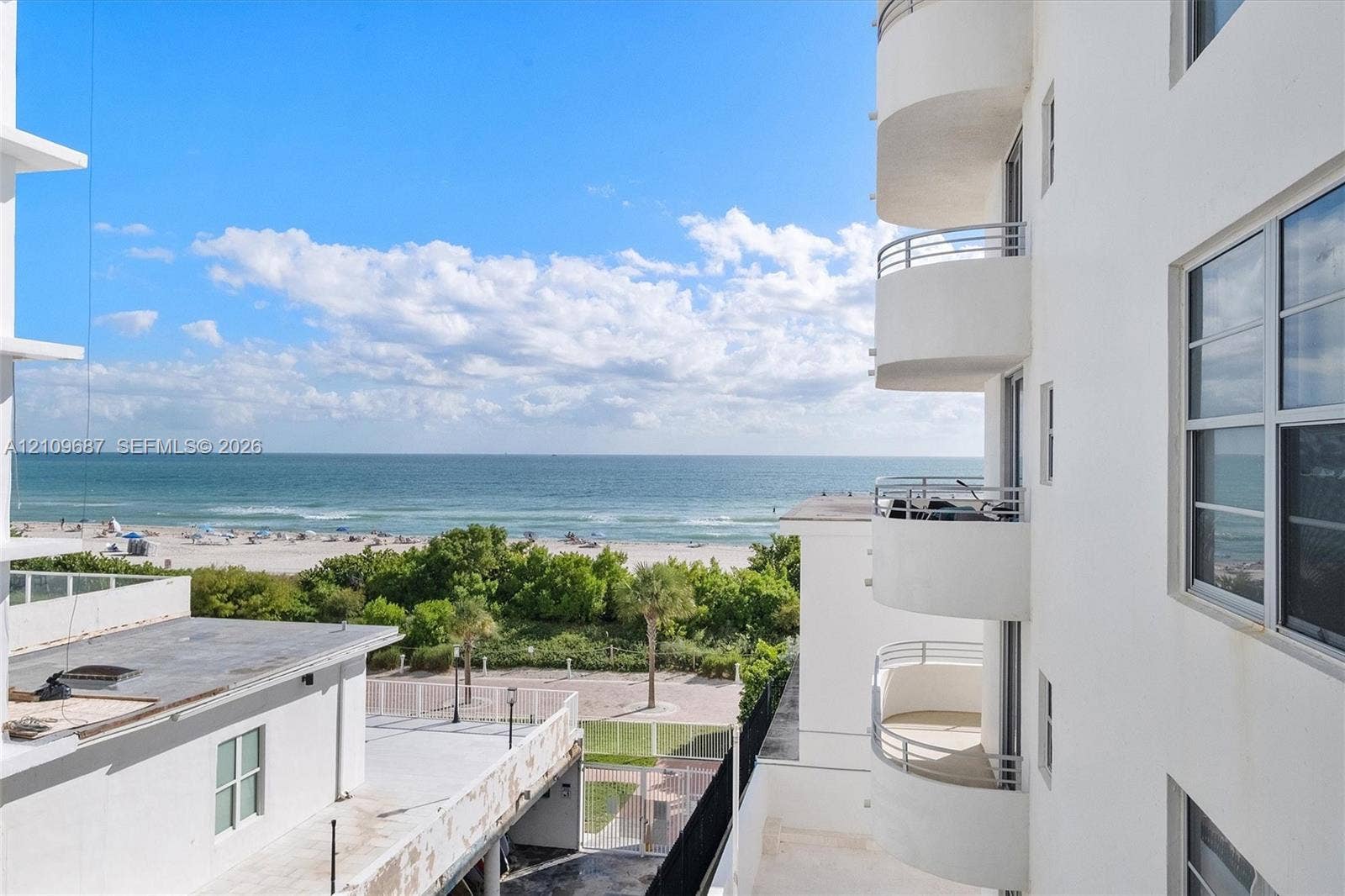 5555 Collins Avenue, #5C, Miami Beach, FL 33140 Stacked semi-circular balconies with metal railings, white stucco exterior, and oceanfront proximity