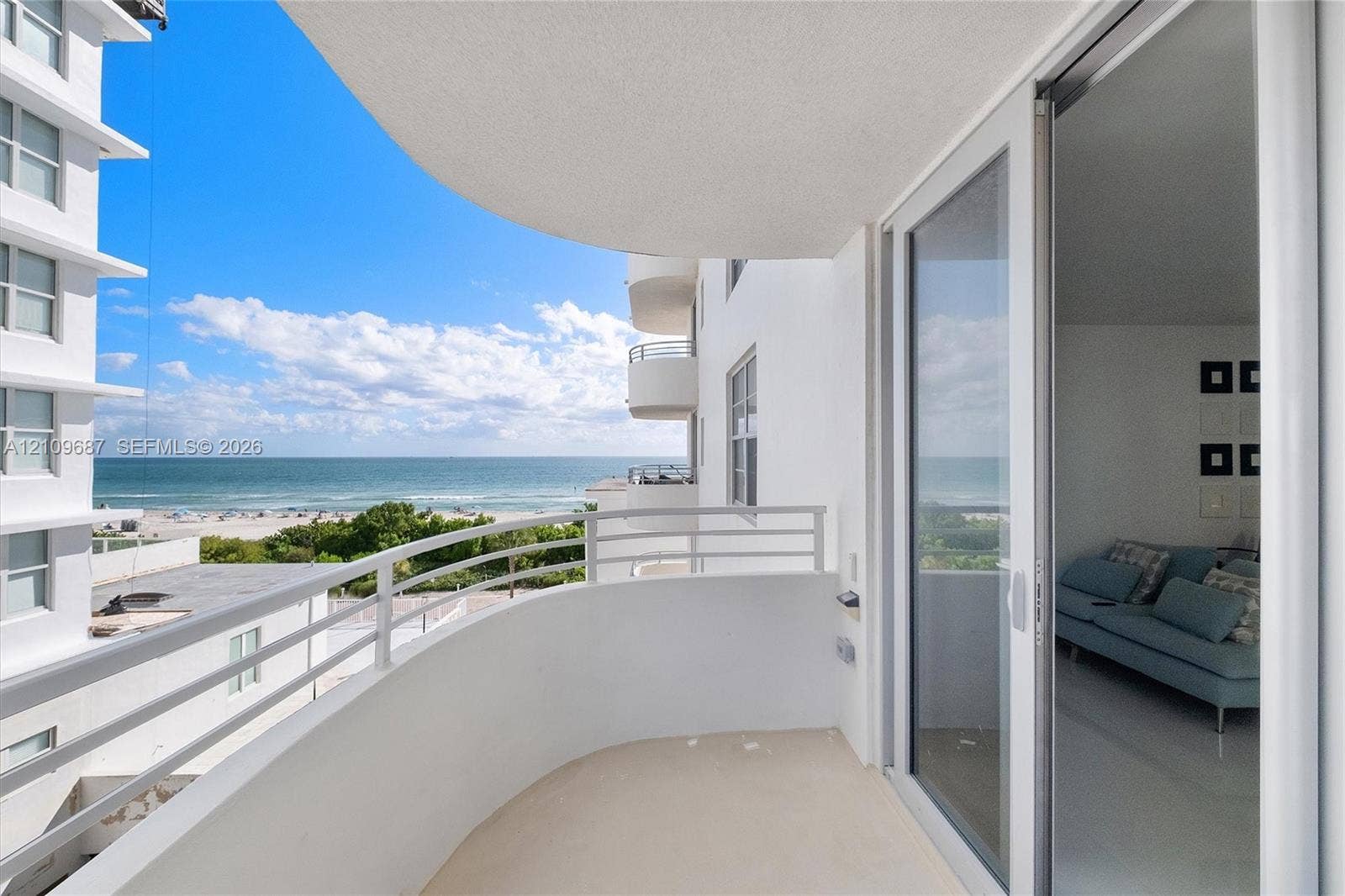 5555 Collins Avenue, #5C, Miami Beach, FL 33140 Curved balcony featuring white solid-wall construction, horizontal metal railings, and sliding glass door entry
