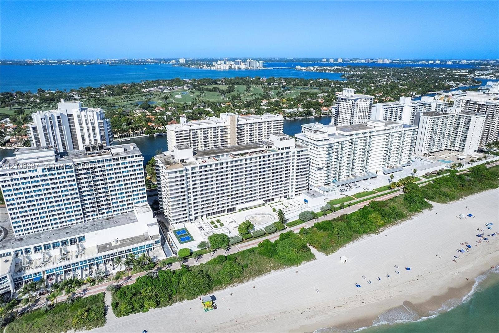 5555 Collins Avenue, #5C, Miami Beach, FL 33140 High-rise residential complex situated on a sandy coastline featuring tennis courts, outdoor swimming pools, and paved walkways