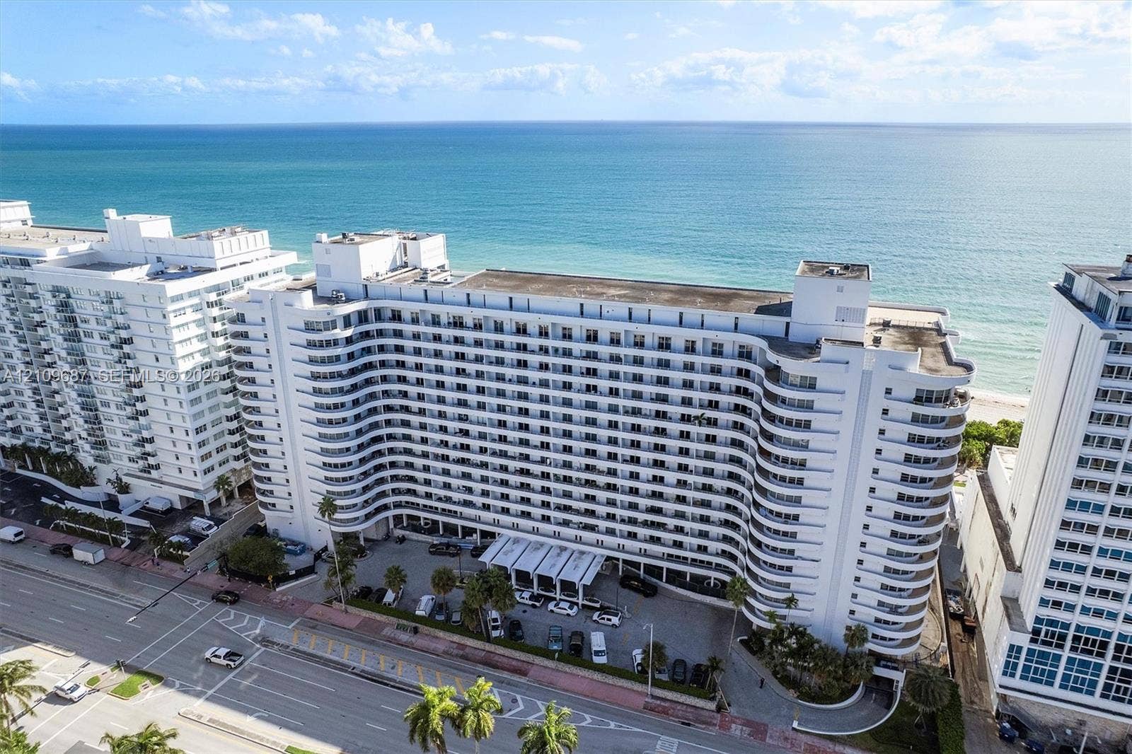 5555 Collins Avenue, #5C, Miami Beach, FL 33140 High-rise residential building featuring a curved architectural design, continuous private balconies, and a direct oceanfront location
