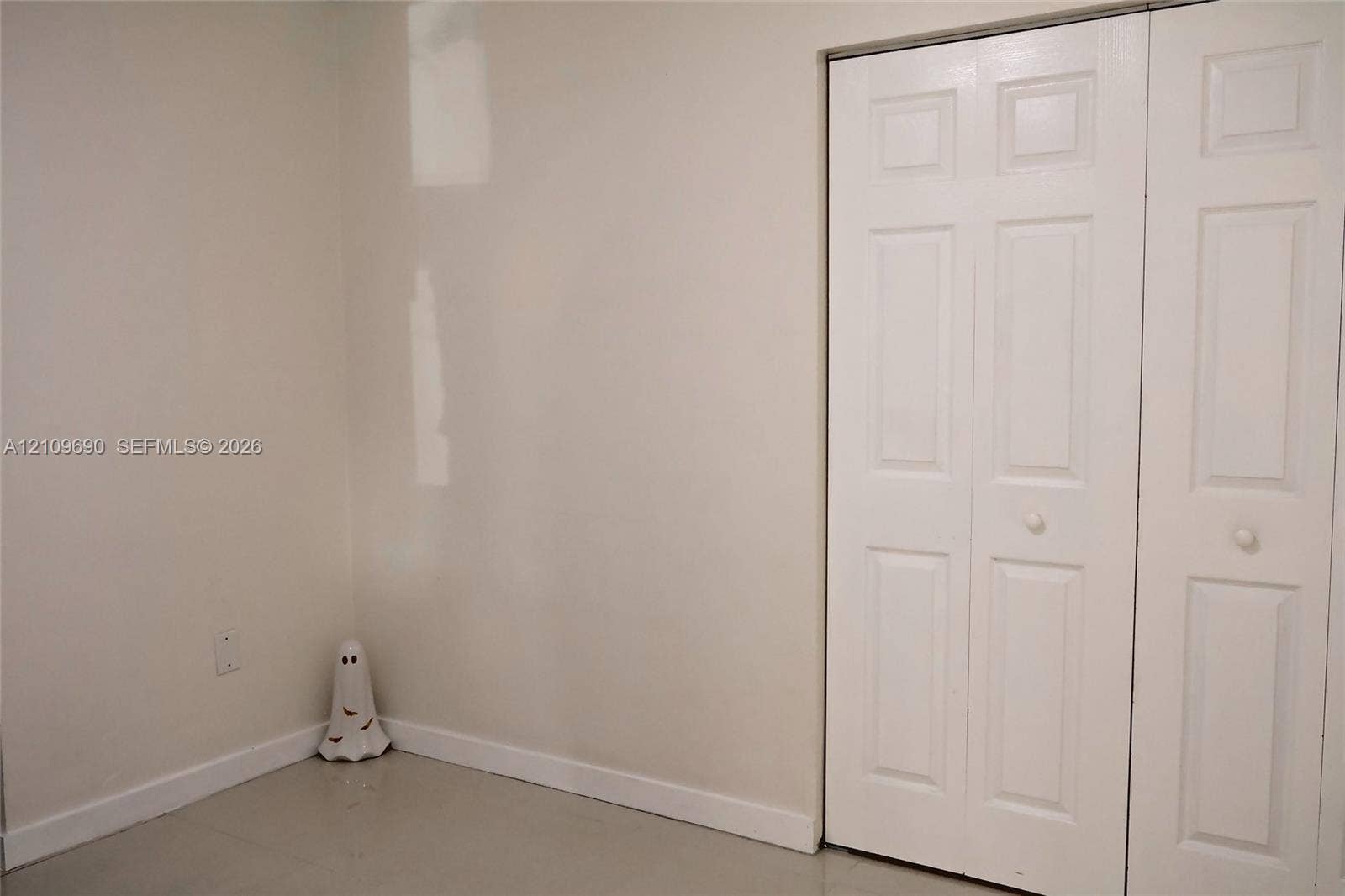 Interior space featuring neutral wall paint and a white bi-fold closet door with recessed panel detailing