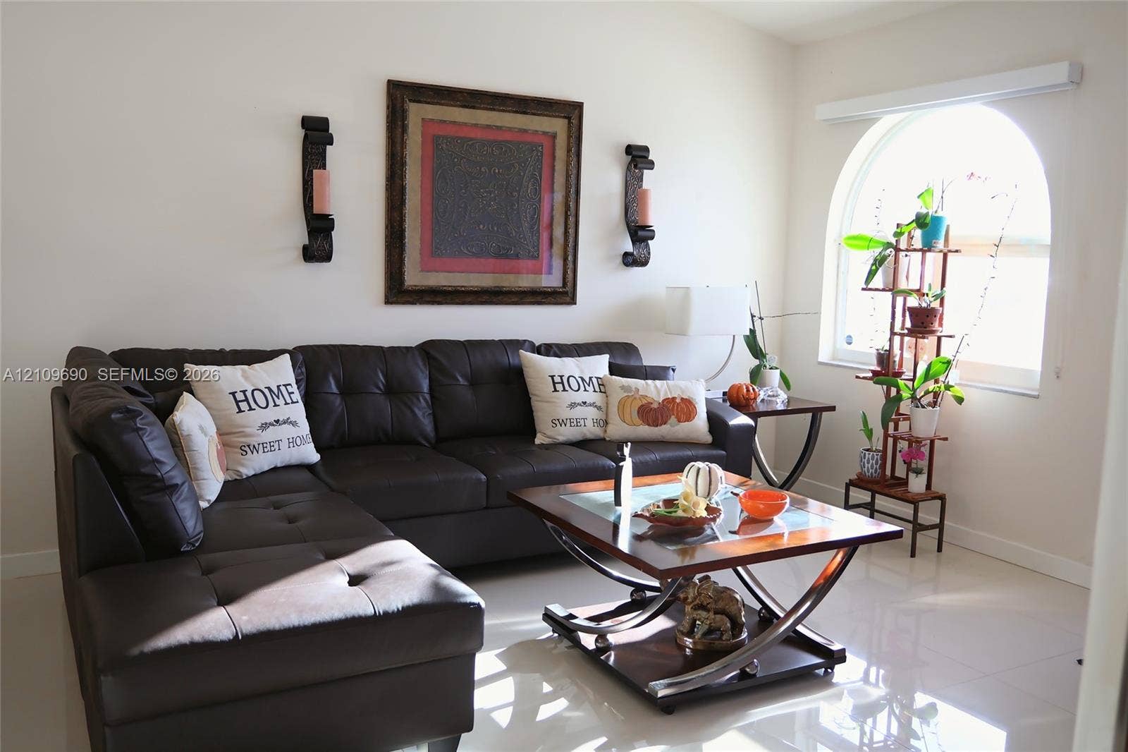 Living area featuring polished tile flooring and a prominent arched window